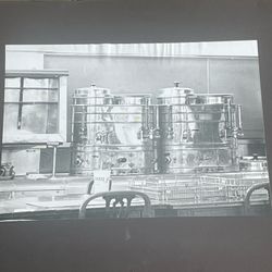 Large antique black and white photo of a pair of large coffee urns
