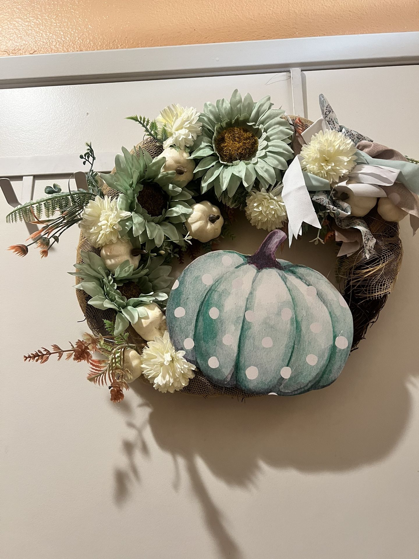 Beautiful wreath featuring a painted pumpkin with green and white polka dots. Adorned with green sunflowers and white flowers. Perfect for any space.