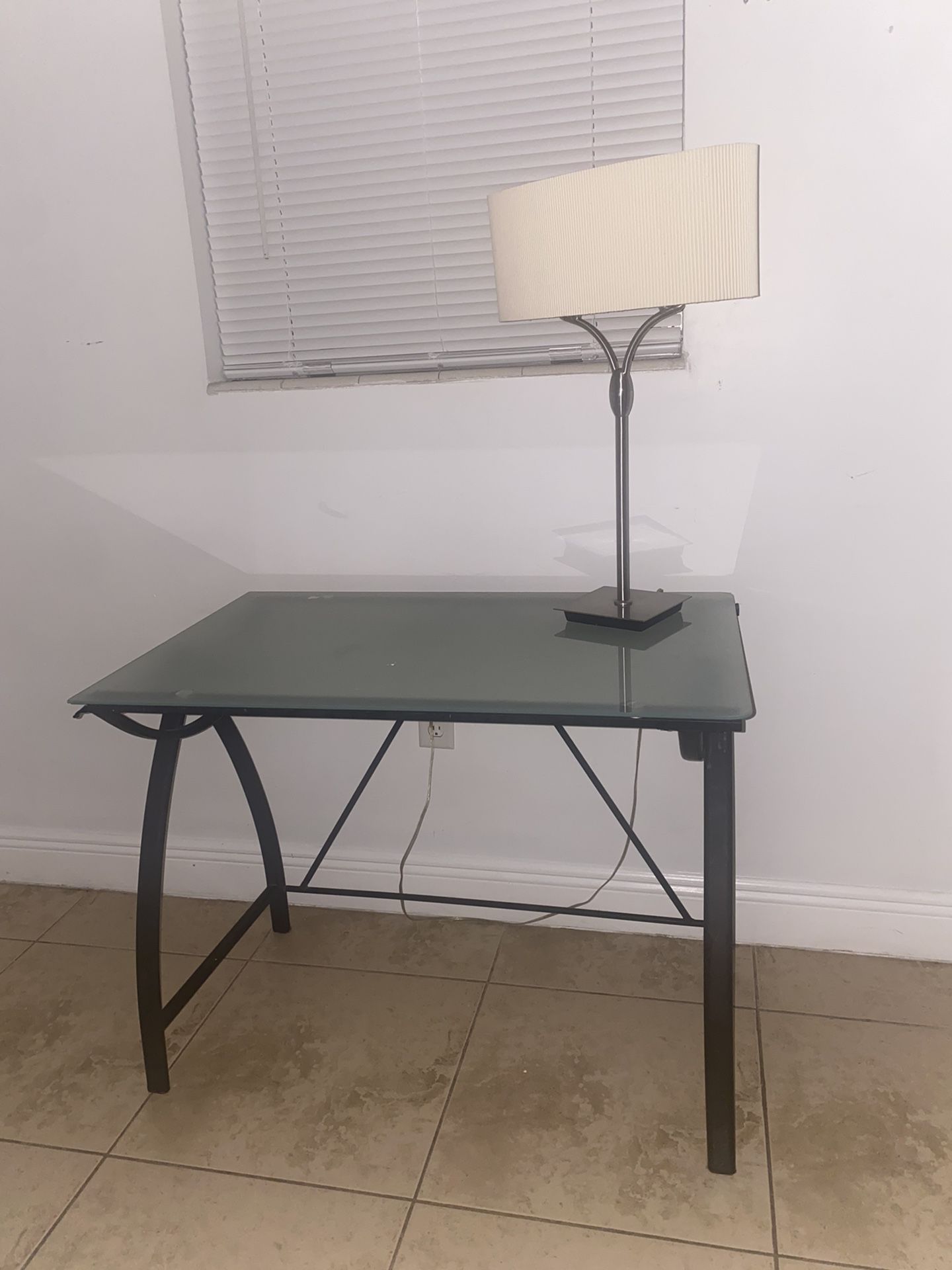 glass desk with lamp and a mattress with its base