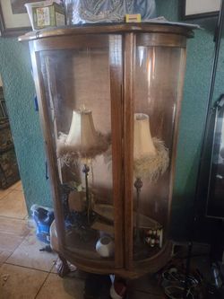 vintage wooden curio cabinet with a curved glass door and front panels
