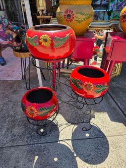 Metal stand with spherical red clay pots decorated with hand-painted flowers.