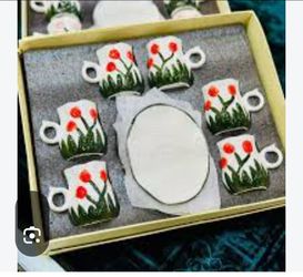 Brand new in original box. Hand painted ceramic set with red tulip design. Includes 6 mugs and 6 oval plates. Each mug is 3 inches high, 2 inches diam