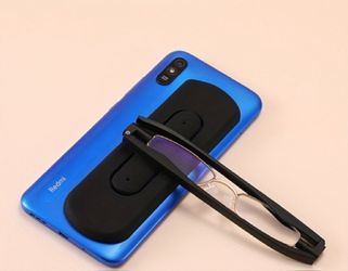 Black folding reading glasses and a case attachable to rear of cell phone