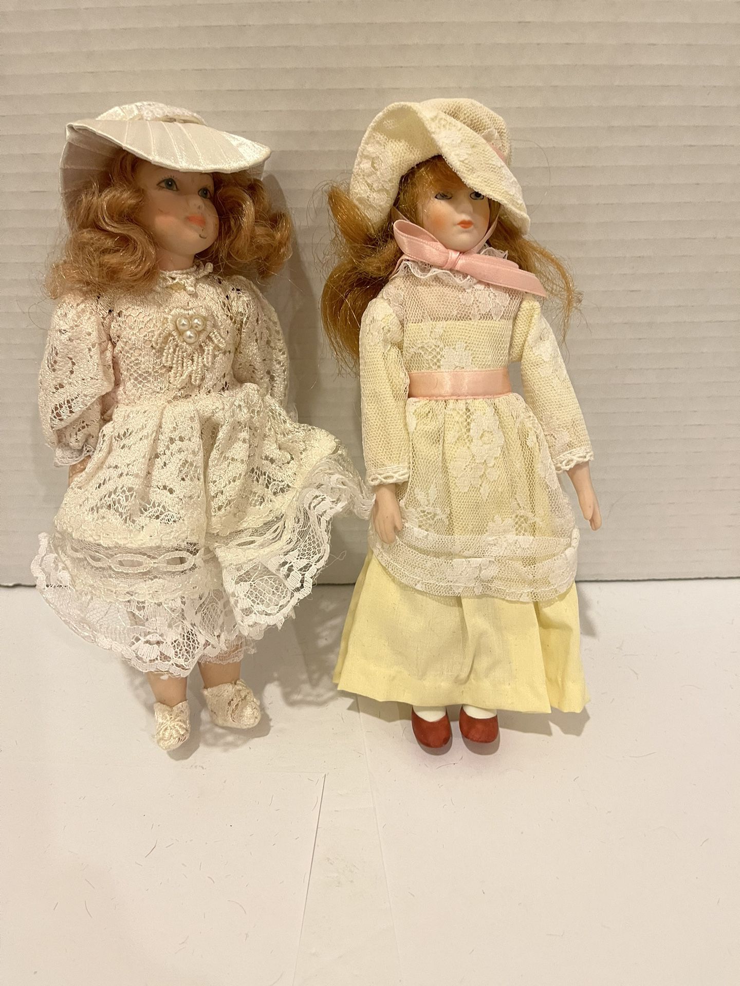 Two porcelain 8” dolls with nice outfits and hats.  The one with the yellow dress is made by Russ. 