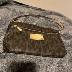 This is a MICHAEL Michael Kors Jet Set Large Signature Wristlet Wallet in brown coated canvas. 
