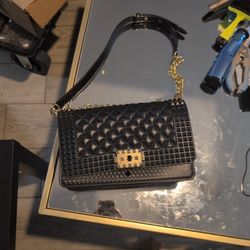 studded quilted shoulder bag with a gold-tone chain strap. This specific design, featuring a mix of diamond quilting and pyramid studs, is commonly fo