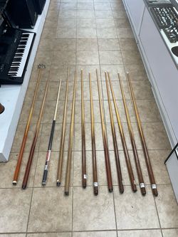 Assorted pool cues and bridge stick