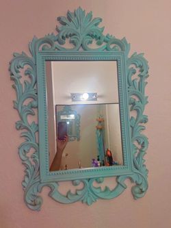 ornate turquoise wall mirror with an elaborate carved-style frame and beaded detailing