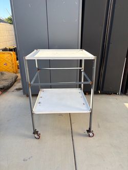 Heavy duty homemade welded rolling cart with two shelves with one drawer and wheels.