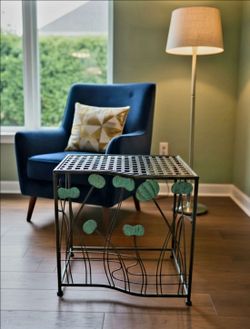 Vintage outdoor Indoor table featuring a black wrought iron frame and green patina lily pad embellishments19.5"×20.5" .