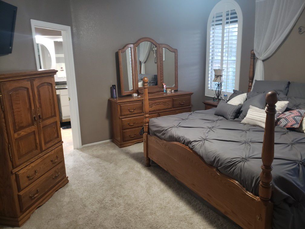 Oak King Bedroom set. Includes 4 post king bed frame, 7 drawer dresser with mirror, 2 drawer end table and armoire.