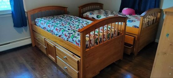 Two twin beds with lower storage drawer units and mattress