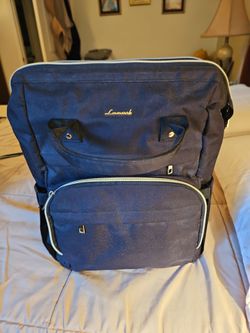 Laptop backpack double top handles with goldtone metal accent and USB charging port.