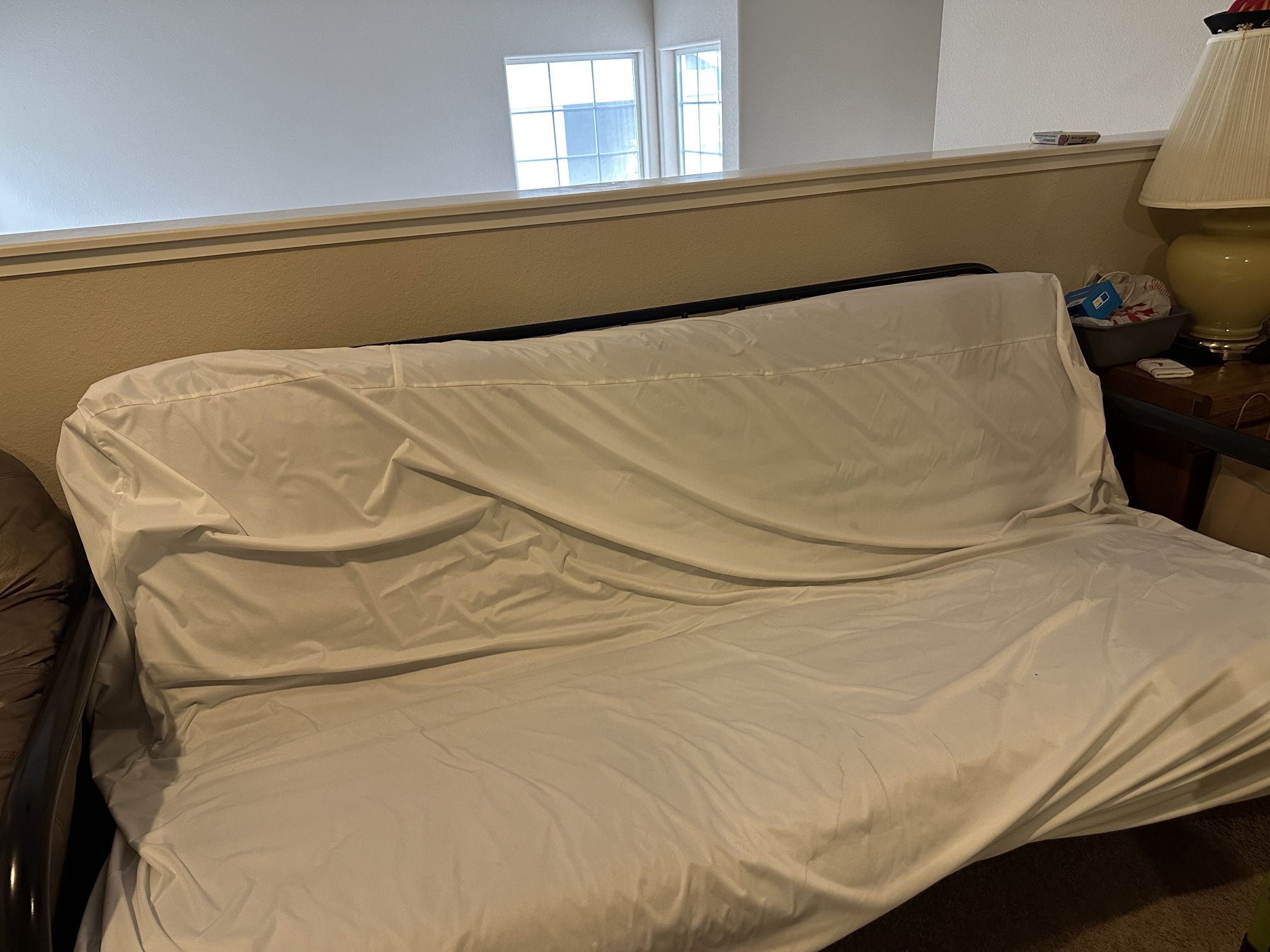 Comfortable sofa/bed with a mattress and white cover, perfect for any room.