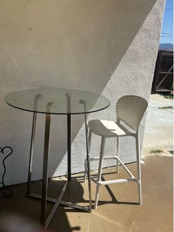 Glass bar table with one high plastic chair