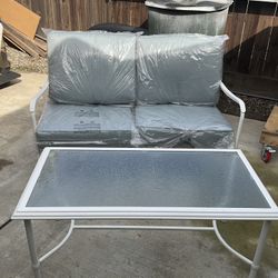 NEW OUTDOOR LOVESEAT AND TABLE WITH GLASS TOP IN WHITE WITH CUSHIONS