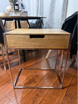 Modern side table with a natural wood drawer and a polished silver metal frame
