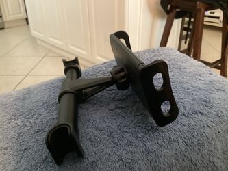 This black, adjustable car headrest mount securely holds tablets and phones for backseat passengers.