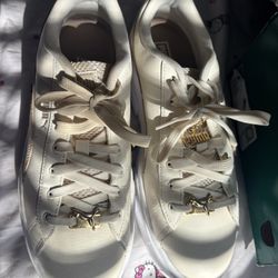 This is a pair of Puma Mayze platform sneakers in a cream or ivory color with gold accents and charms.