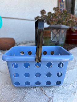light blue plastic storage or shopping basket with a black handle and circular vent holes