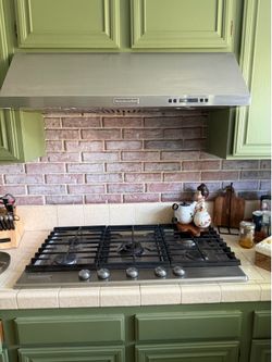 Stainless steel KitchenAid gas cooktop with four burners and range hood