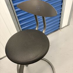 A modern metal bar stool with a padded fabric seat and a small metal backrest