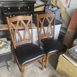 Two solid oak Chairs With Real Black Leather Seats.