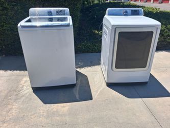 Functional Samsung washer and dryer set in white. The top-load washer has a damaged control panel with a hole in the plastic casing. The front-load dr