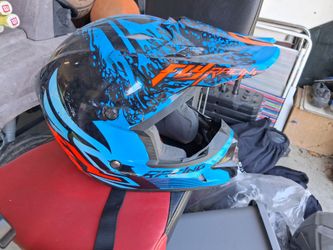 Fly Racing helmet features a vibrant blue and black splatter graphic design with orange accents.