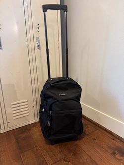 Black Rockland rolling backpack with extendable telescoping handle, multiple zip compartments, and a side mesh pocket. Compact carry-on size with inli
