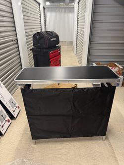 portable folding bar table or tradeshow podium table featuring a black tabletop, aluminum frame, and a detachable black fabric skirt