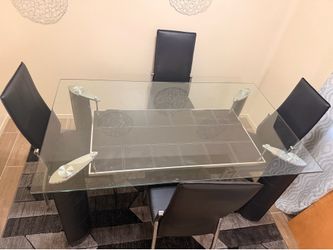 Beautiful glass dining table with 4 black leather chairs.