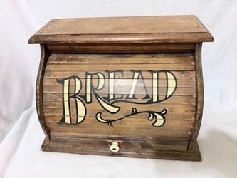vintage wooden roll-top bread box with painted "BREAD" lettering across the curved tambour door and a small wooden knob handle.