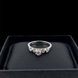 This is a gold five-stone diamond ring with a round center diamond and four smaller round diamonds set in the band. 