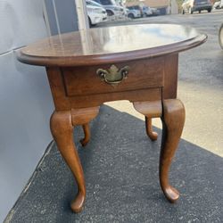 This item is a vintage Broyhill Queen Anne style side table featuring a rich wood finish, cabriole legs, and a single drawer with a brass pull.