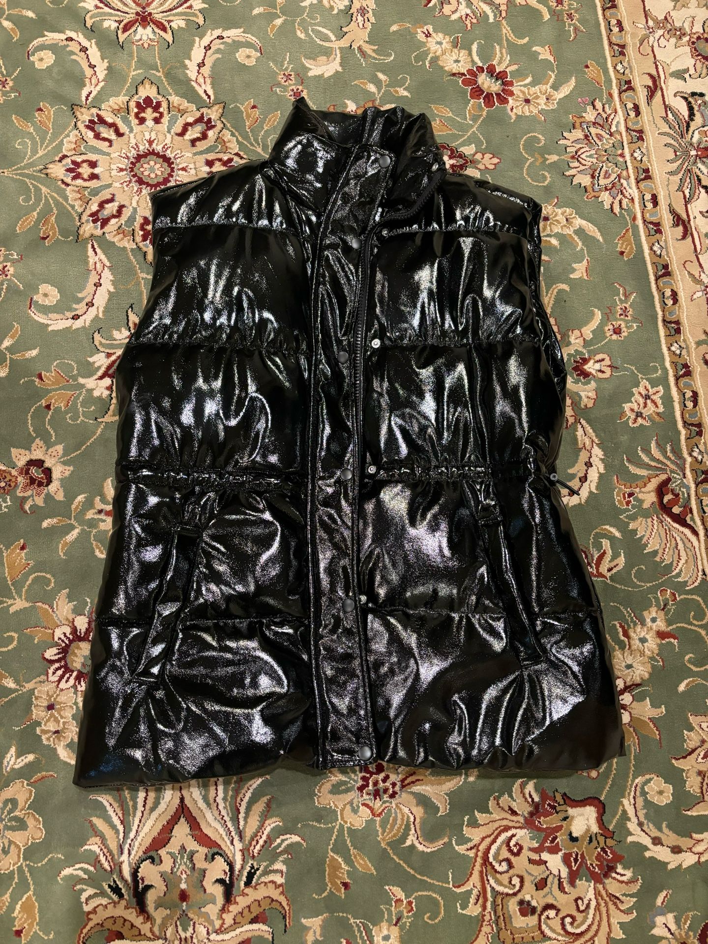 Black puffer metallic long vest with adjustable straps, zipper and buttons.