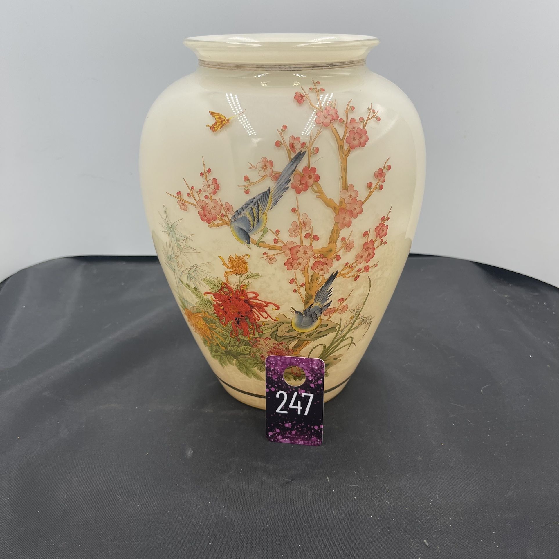 This vintage Asian-style vase features a beautiful design with a blue bird, cherry blossoms, and butterfly motifs. Made of glass with gold trim, this