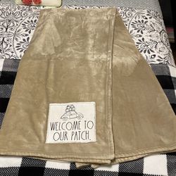 Rae Dunn beige plush blanket with a "Welcome to Our Patch 