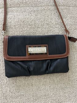 Chaps black faux leather crossbody bag with brown trim and a flap closure.