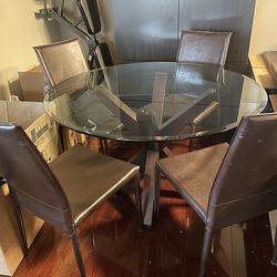 ROUND GLASS dining table and four dark brown chairs