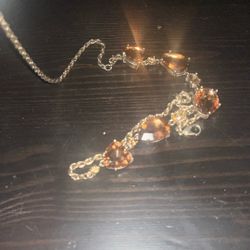 The necklace pictured is a gold-toned necklace featuring several faceted amber-colored citrine gemstones set in a stylized arrangement. 