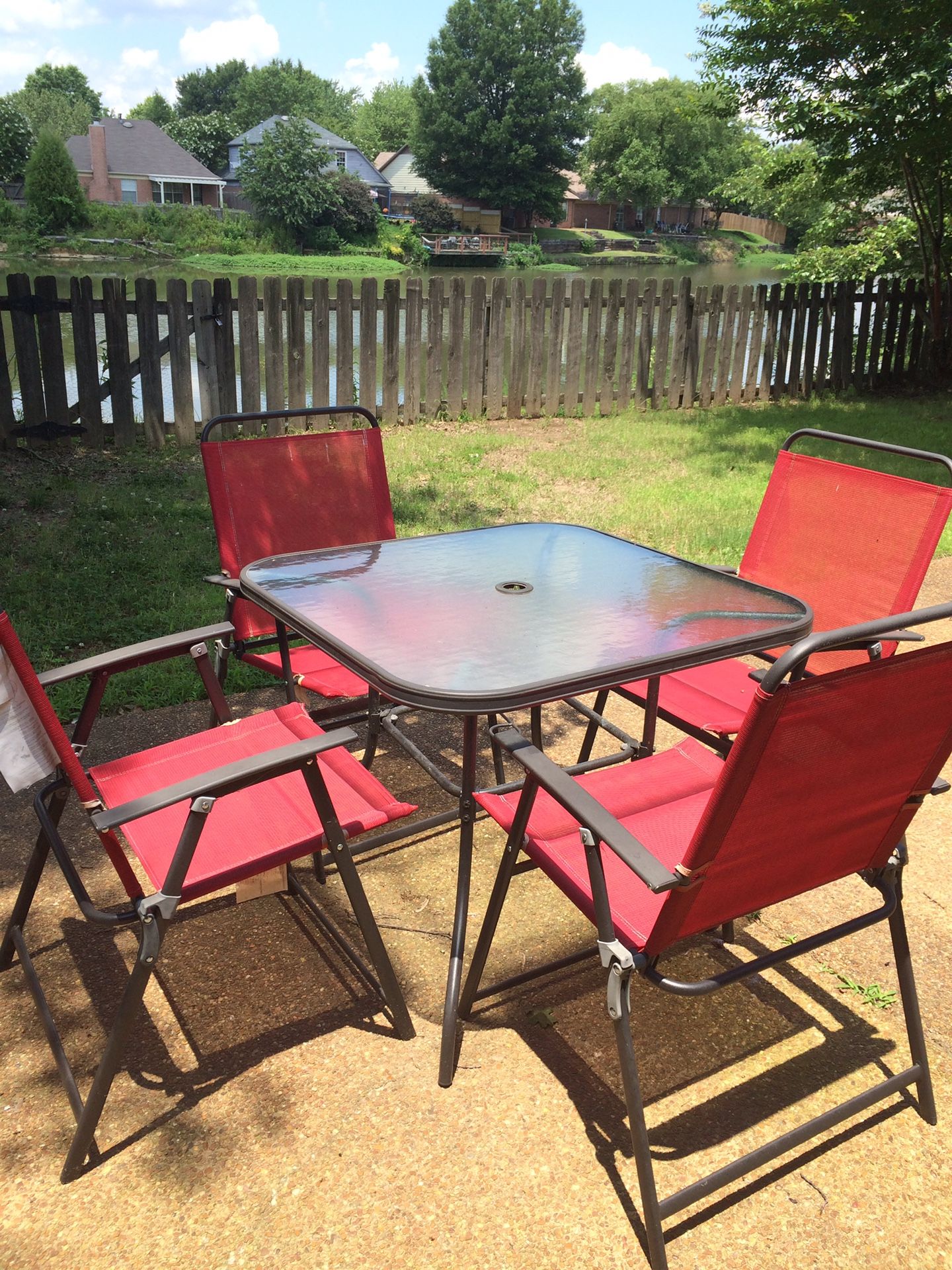 Glass outside table with 4 red chairs
