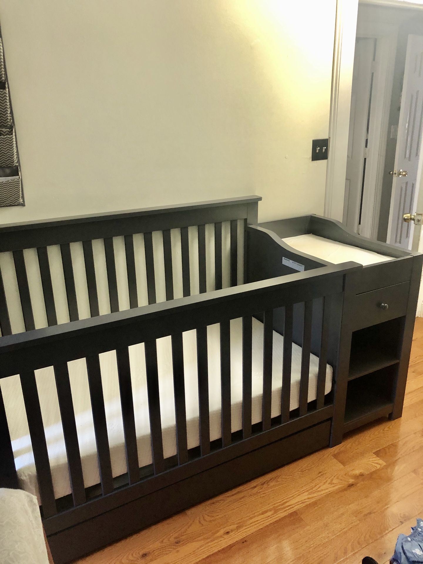 Baby crib with mattress and changing table.