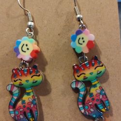 Rainbow cat earrings with smiley flower accents.