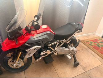 This is a red and gray Rollplay BMW R1200 GS battery-powered ride-on toy motorcycle