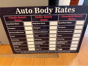 A wall-mounted sign detailing auto body labor rates based on a "Flat Rate Guide". $35
