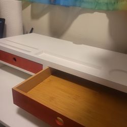 White monitor stand/riser with 2 orange drawers and storage cutouts