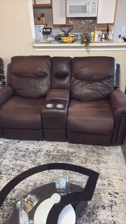 Brown leather love seat with center console and reclining seats