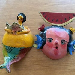 Mexican folk art in the form of a mermaid figure and two masks made from coconut shells