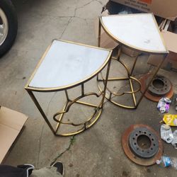 two modern faux marble side tables with gold metal frames and a half-moon or D-shaped design. 